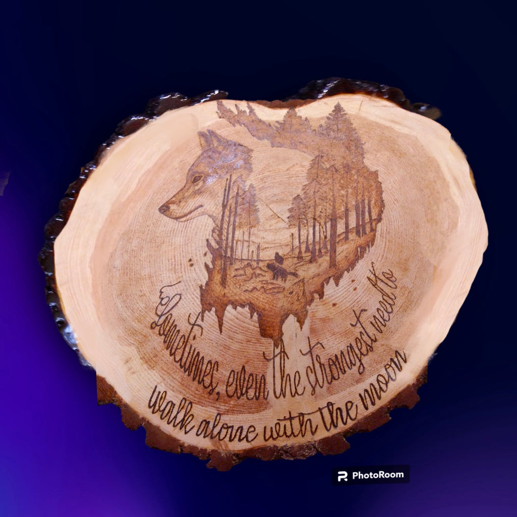 wood tree slice with burned wolf scene and writing
