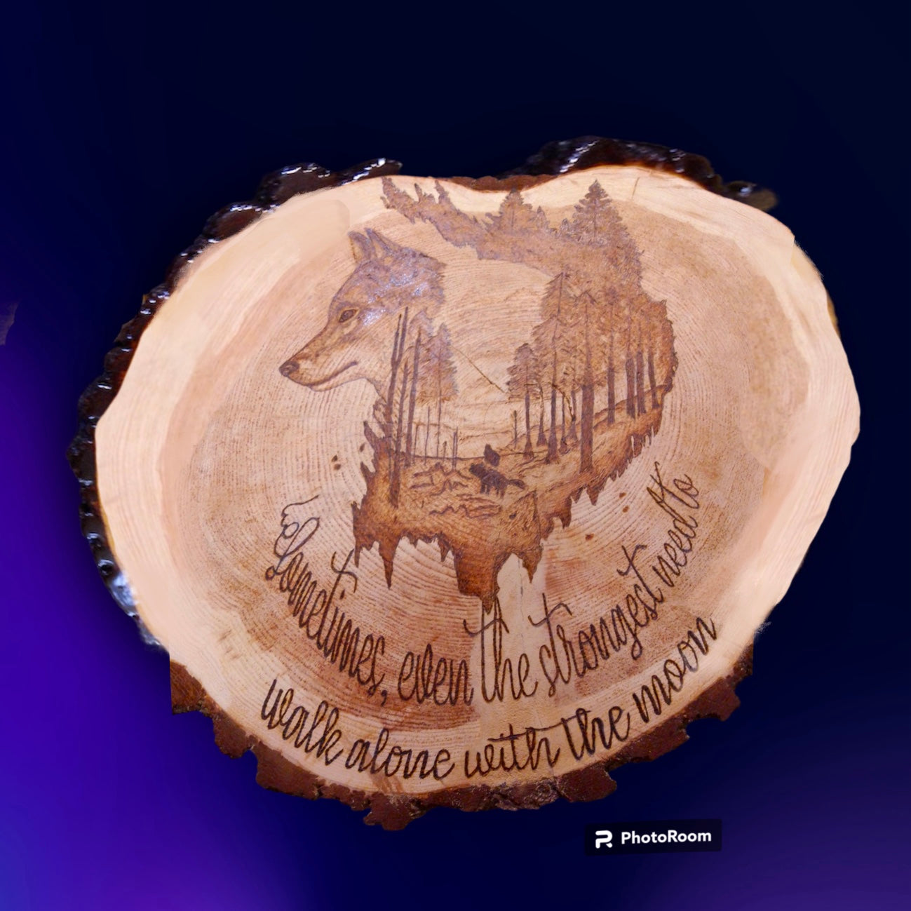 wood tree slice with burned wolf scene and writing
