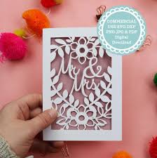Hand holding a decorative card with floral cut-out design on a pink background