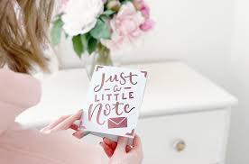 Person holding a card with 'Just a little note' text in a soft, blurred indoor setting.